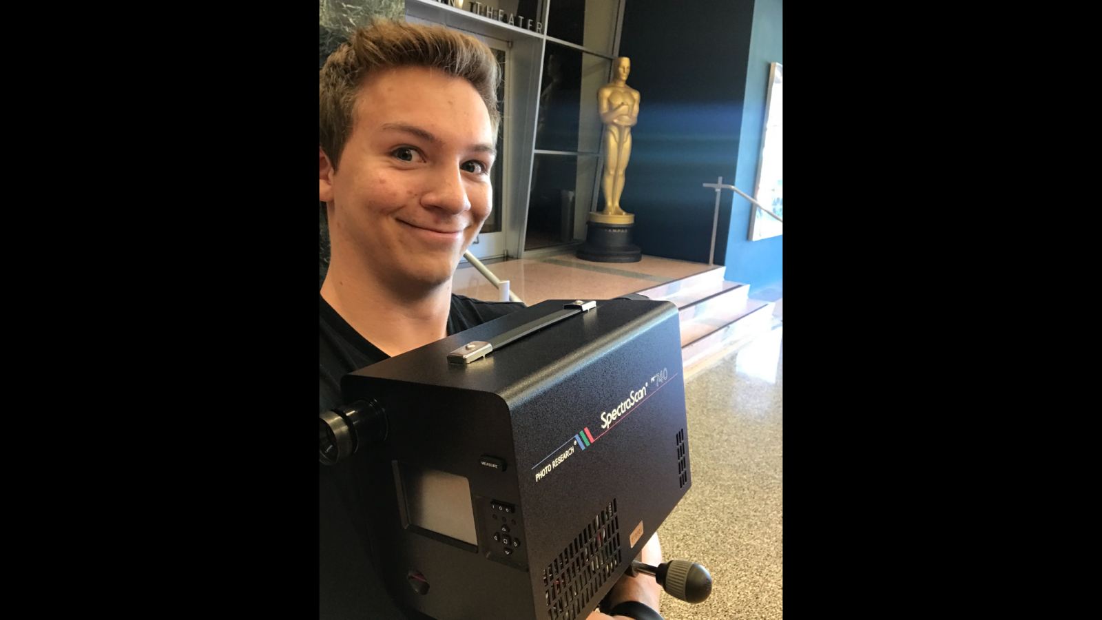 Andrew Sevigny poses for a photo while holding a large video camera.