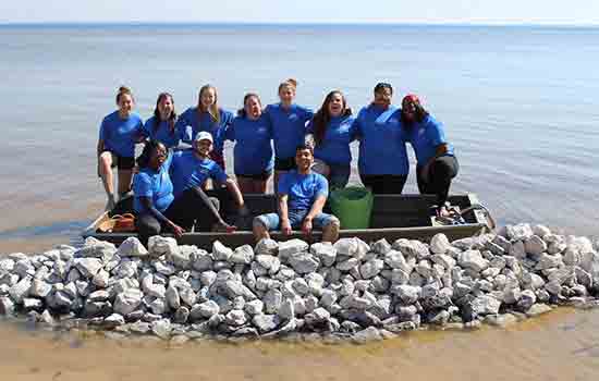 a group of students that participated in alternative spring break posing on a beach
